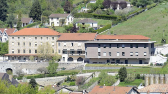 vue aérienne de la façade d'un grand bâtiment de trois niveaux construit sur un terrain en pente
